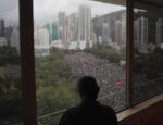 Osoba sa pozerá z okna na protest v parku Victoria v Hongkongu. Zdroj foto: TASR/AP Photo/Kin Cheung)